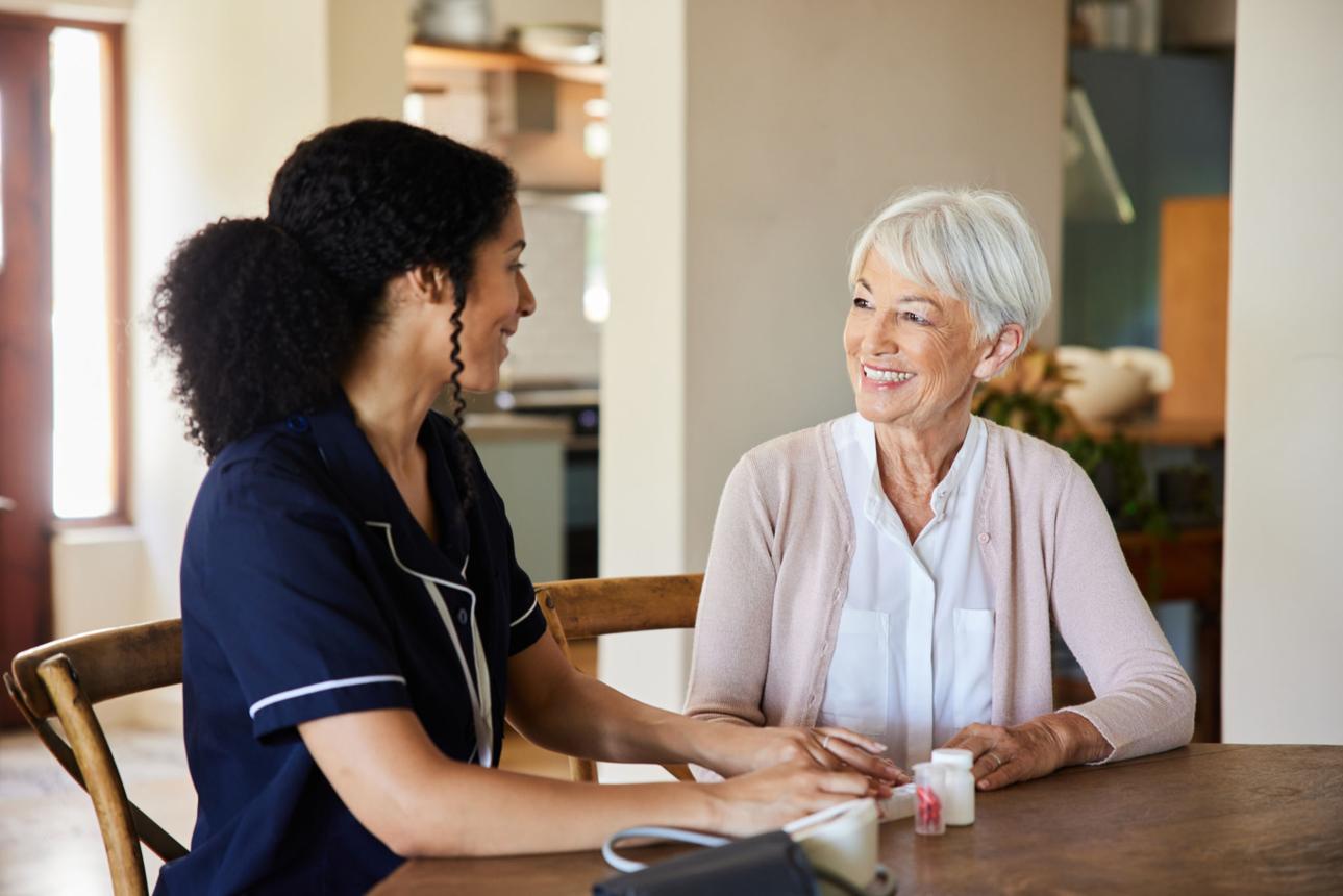 Companion and elderly client sharing a warm conversation at home
